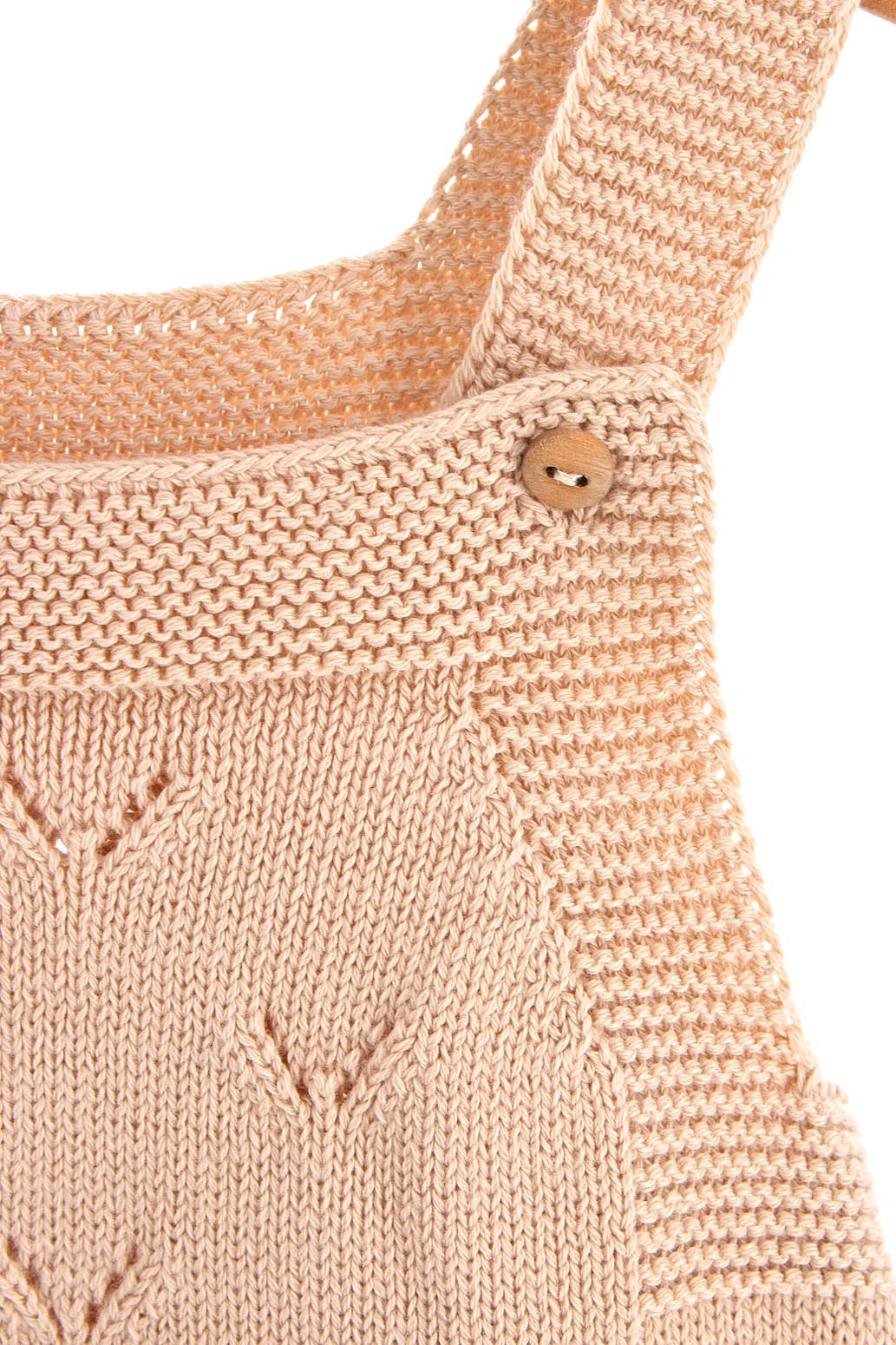 Close-up of a soft cotton knit jumpsuit strap with a wooden button, showcasing the V pattern design.