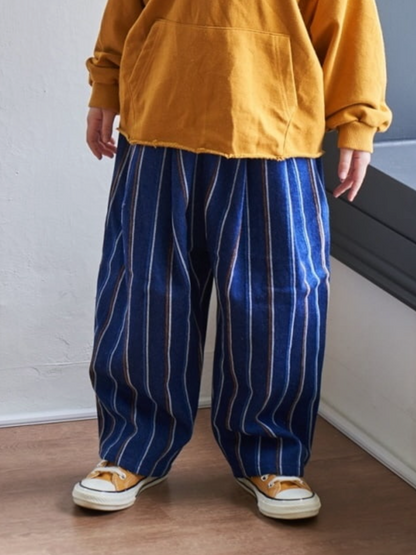 Child wearing oversized baggy striped denim pants with a yellow hoodie and sneakers, showcasing comfort and style.